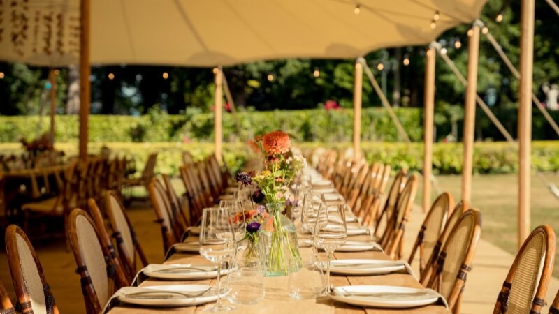 Outdoor wedding table arrangement with chairs and a tent